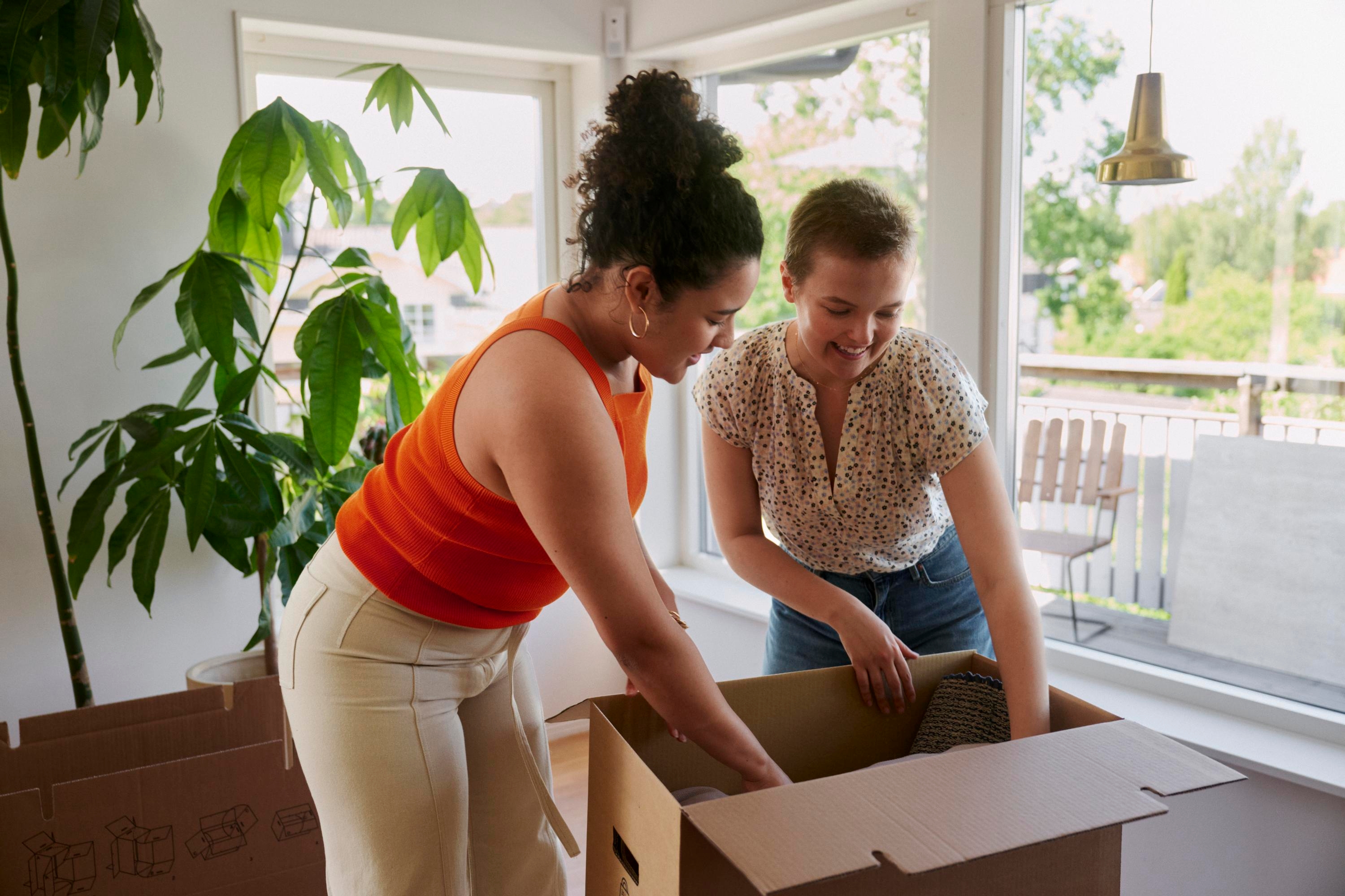 Två unga kvinnor packar i en flyttkartong